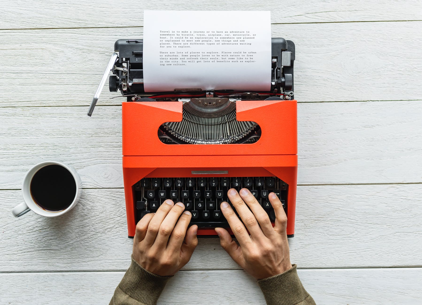 person holding black and orange typewriter